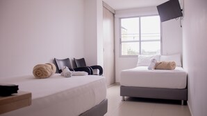 Ett modernt hotellrum med två sängar, en platt-TV som är monterad på väggen och ett stort fönster med utsikt över staden.
