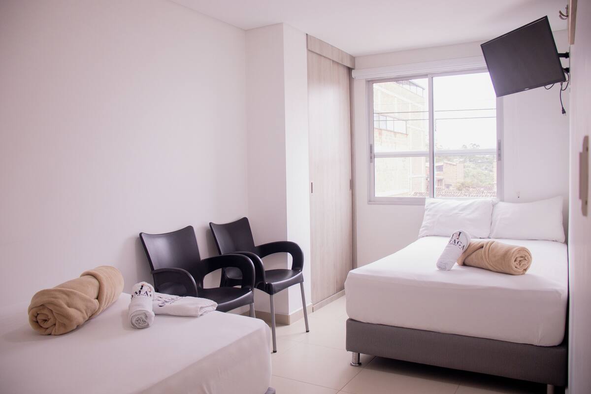 Una habitación de hotel con dos camas, un televisor y una ventana con vistas.