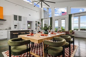 Moderni keittiö, jossa on ruokailutila, suuret ikkunat ja näkymä ulos.