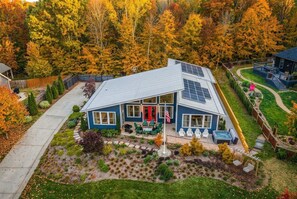 Una casa de dos pisos con paneles solares, una puerta roja y un jardín bien cuidado.