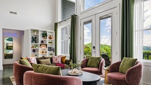 A modern living room with a sofa set, a coffee table, and a bookshelf. - Fall Mtn Views | Hot Tub · Game Room · 10m AVL (Asheville)