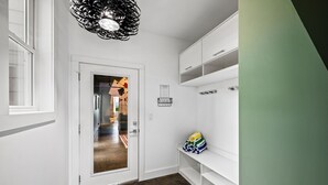 A hallway with a white door, a mirror, a shelf with bags, and a green wall. - Fall Mtn Views | Hot Tub · Game Room · 10m AVL (Asheville)