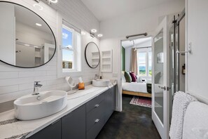 Een moderne badkamer met een grote spiegel, twee wasbakken en een douche.