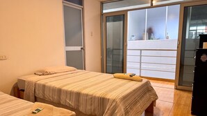 A hotel room with two beds, a sliding glass door to a balcony, and a minibar.