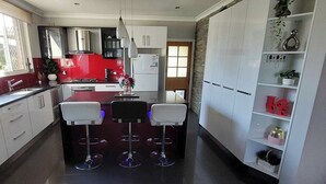 Une cuisine moderne avec un îlot central, des armoires blanches et un mur d’accent rouge.