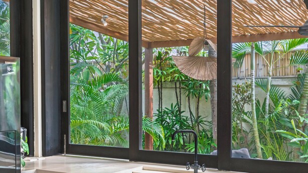 Un baño moderno con un ventanal grande, un ventilador de techo y un lavabo con cortina de ducha de bambú.