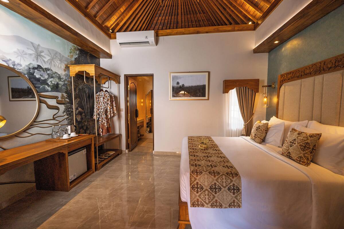 A bedroom with a large bed, wooden headboard, and a mural on the wall.
