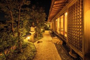 Un chemin mène à un bâtiment traditionnel, doté d’une entrée carrelée et d’une lanterne.