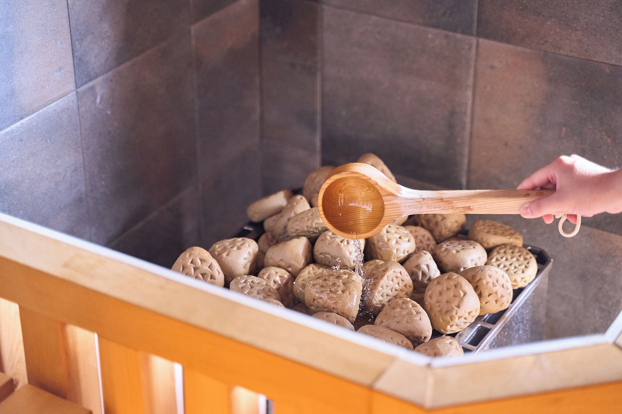 A hand pouring water into a container filled with round, textured objects.