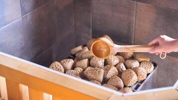 A hand pouring water into a container filled with round, textured objects.