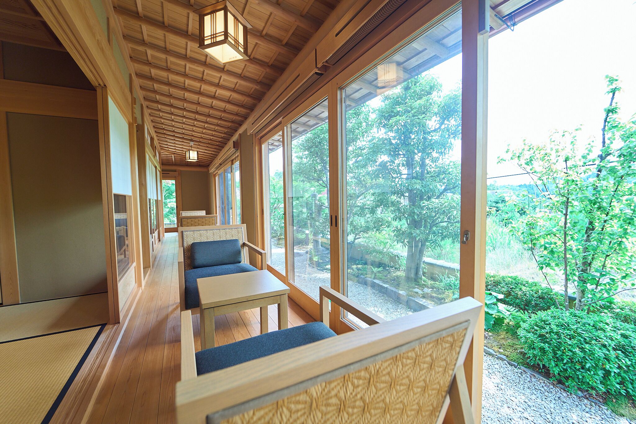 A corridor with wooden walls, large windows, and seating areas.
