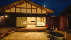 A modern building with a large glass door entrance, a stone patio, and two large tubs outside. - Keyaki no yado En (Koka)