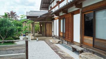 A traditional Japanese building with a wooden exterior, large sliding doors, and a gravel pathway leading to a wooden bench.