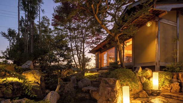 A traditional Japanese-style building with a wooden exterior, stone pathway, and illuminated lanterns. - Keyaki no yado En (Koka)