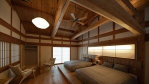 A traditional Japanese-style bedroom with tatami flooring, a low ceiling with exposed beams, a ceiling fan, and a shoji screen window. - Keyaki no yado En (Koka)