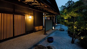 A traditional Japanese building with a wooden exterior, a gravel pathway, and a small tree. - Keyaki no yado En (Koka)