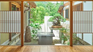 A traditional Japanese room with tatami flooring, a shoji screen, and a view of a garden with a bonsai tree. - Keyaki no yado En (Koka)