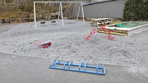A playground with a swing set, a tire swing, a red tricycle, and a blue play structure. - Gorgeous apartment with WiFi (Godvik)