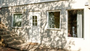 A building with a set of concrete steps leading to a door, two windows, and a small outdoor area with a metal grate. - Gorgeous apartment with WiFi (Godvik)
