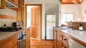 Una cocina con gabinetes de madera, estufa, fregadero y refrigerador.