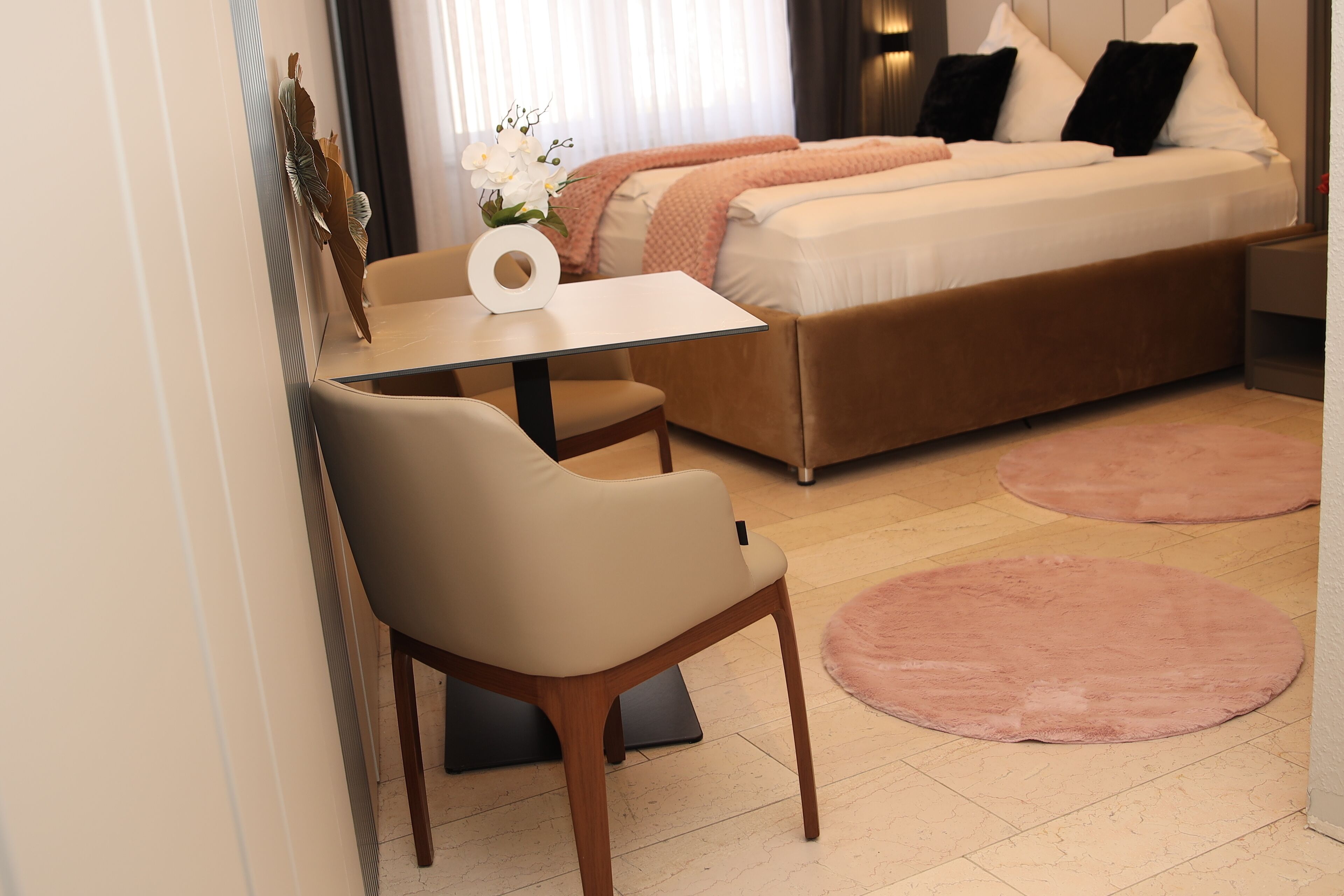 A modern bedroom with a bed, a small table, a chair, and a decorative vase.