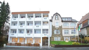 A multi-story hotel with balconies, a stone facade, and a flag. - Hotel Hafez (Bad Salzuflen)