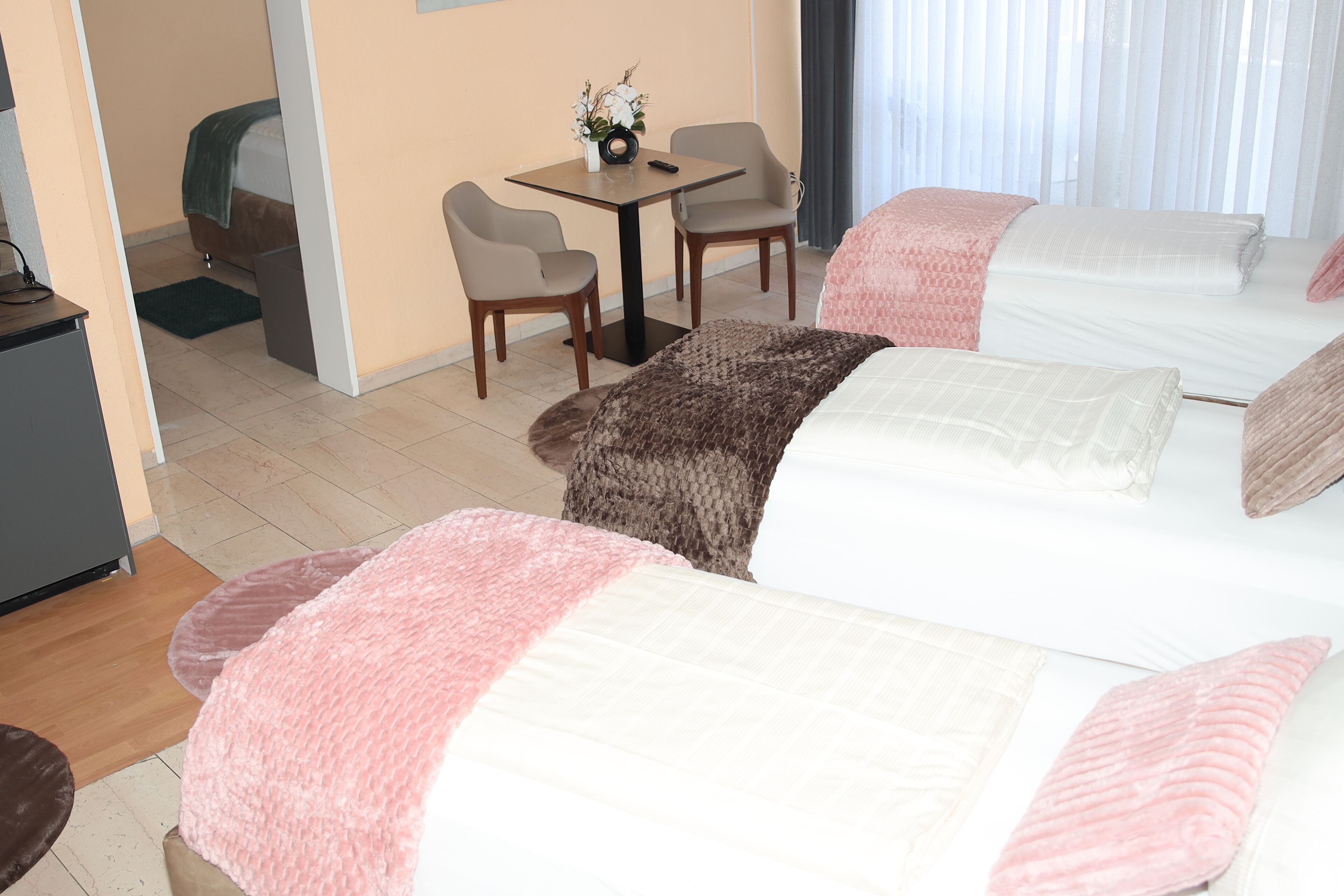 A hotel room with two beds, a desk, and a chair.