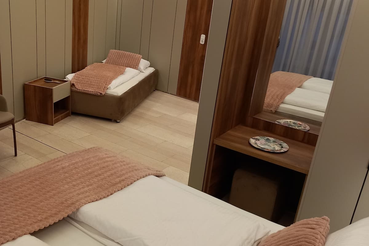 A modern hotel room with two beds, a wooden vanity, a mirror, and a small table with a plate.