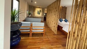 A modern interior with a wooden floor, a sofa, a bed, and a bamboo partition. - Eco Lagoon (Mang Yang)