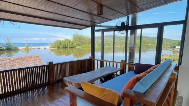 A wooden deck with a bench and table, overlooking a lake with a clear view of the surrounding landscape. - Eco Lagoon (Mang Yang)