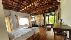 A room with two beds, wooden flooring, a dining table, and large windows with curtains. - Eco Lagoon (Mang Yang)