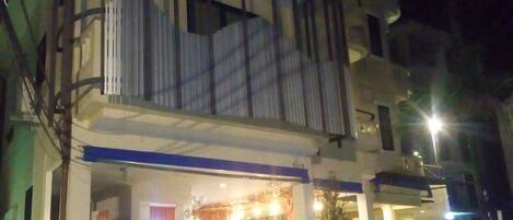 A building with a balcony, a parked car, and a motorcycle.
