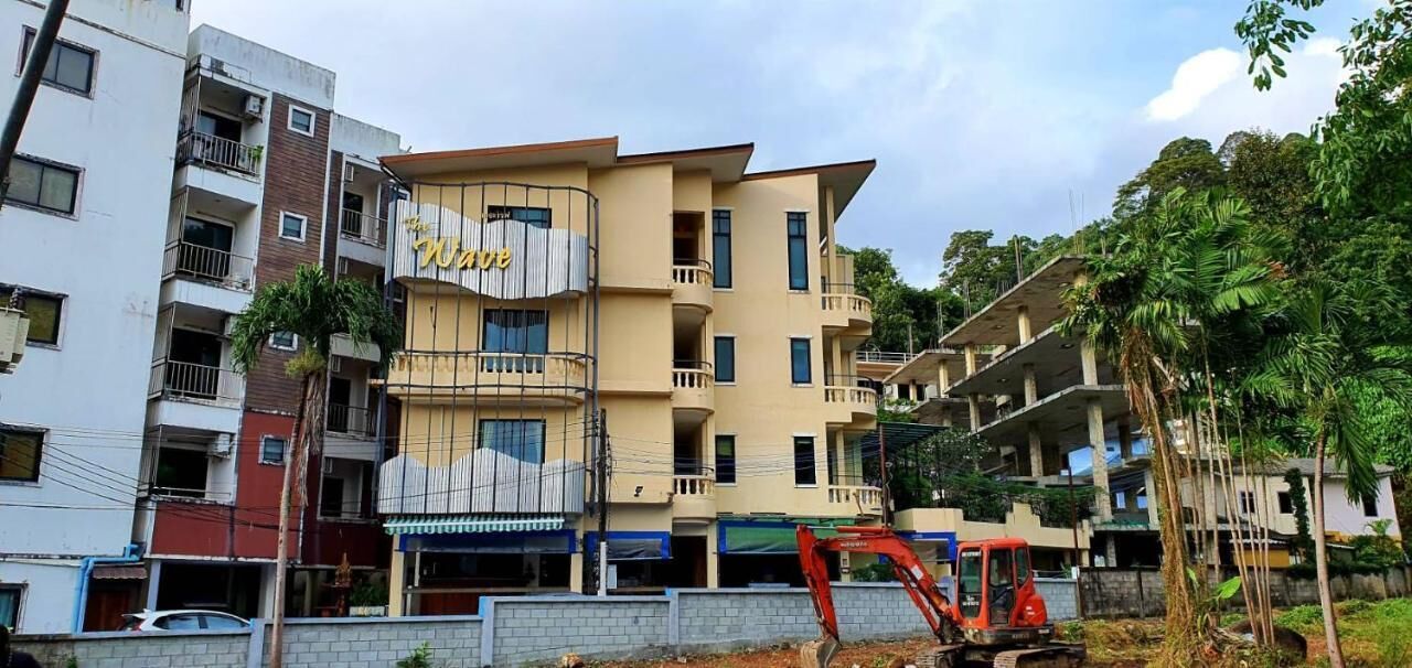 A multi-story building with balconies, a visible sign that reads "Hotel," and construction equipment in the foreground.