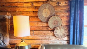 Una habitación acogedora con pared de madera, un sofá, una lámpara y placas decorativas.