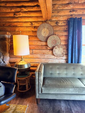 Habitació acollidora amb paret de fusta, un sofà, una làmpada i plats decoratius.