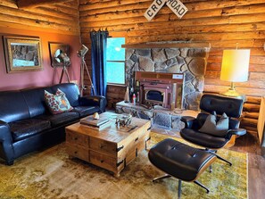 Un intérieur chaleureux de chalet en bois, avec une cheminée en pierre, des meubles en cuir et une décoration rustique.