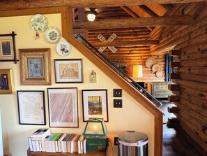 Een kamer met een houten trap, ingelijste foto's en een boekenverzameling.