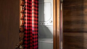 Un cuarto de lavandería con una lavadora blanca y una cortina a cuadros rojos y negros.