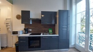 Una cocina moderna con armarios oscuros, microondas, cafetera y una bolsa verde sobre la encimera.