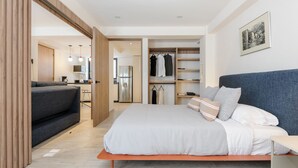 Un dormitorio moderno con cama, armario, zona de estar y kitchenette.