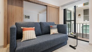 Una sala de estar moderna con un sofá gris, paneles de madera y vistas a un balcón.
