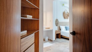 Ein Schlafzimmer mit einem Holzschrank, einem Nachttisch, einem Bett mit Kissen und einer Wandleuchte.