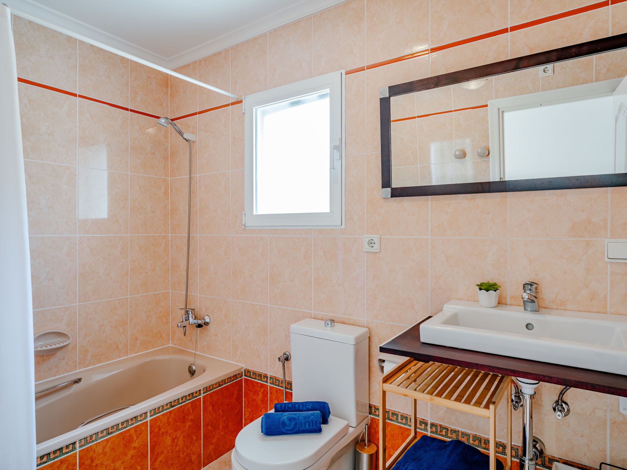 Une salle de bain avec une baignoire, des toilettes, un lavabo et une fenêtre.
