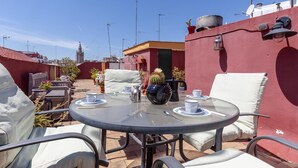 Eine Dachterrasse mit rundem Tisch, Stühlen und Blick auf die Skyline der Stadt.