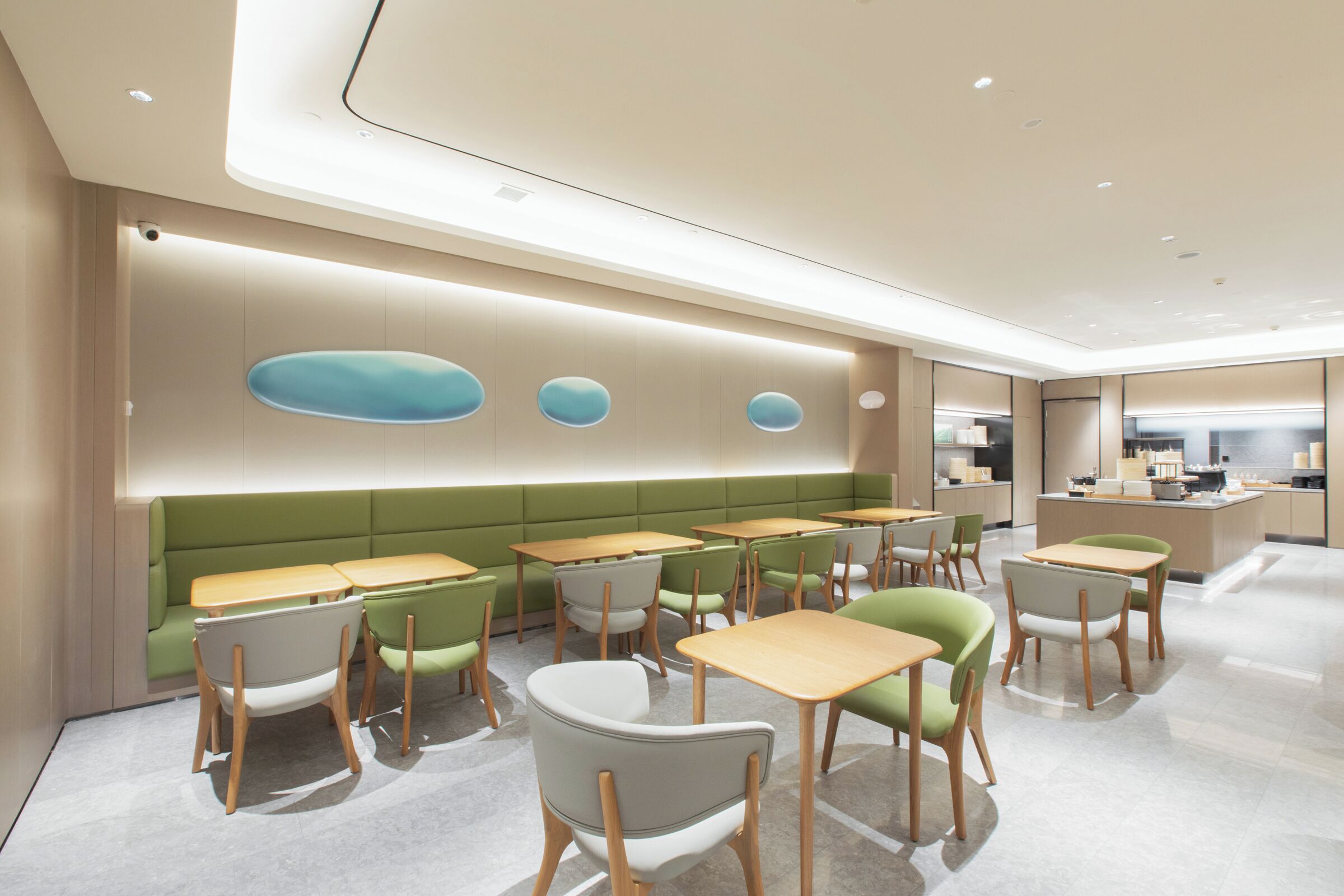 A modern restaurant with green booths, wooden tables, and a clean, minimalist design.