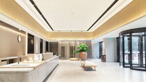 Eine moderne Lobby mit einer Rezeption, einer Sitzecke und einer großen Pflanze.