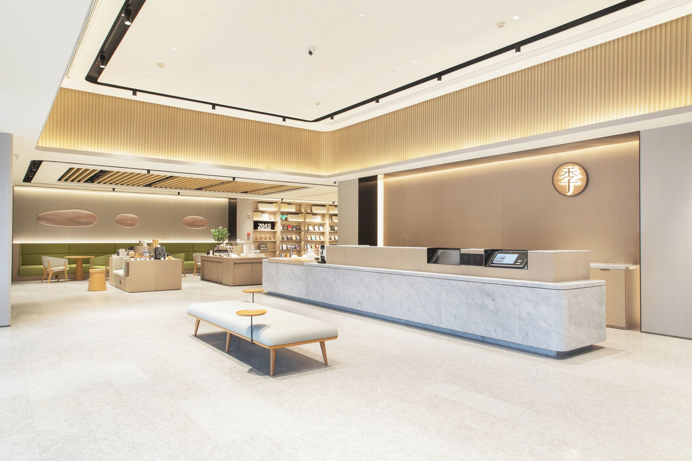 A modern hotel lobby with a reception desk, seating area, and a large bookshelf.