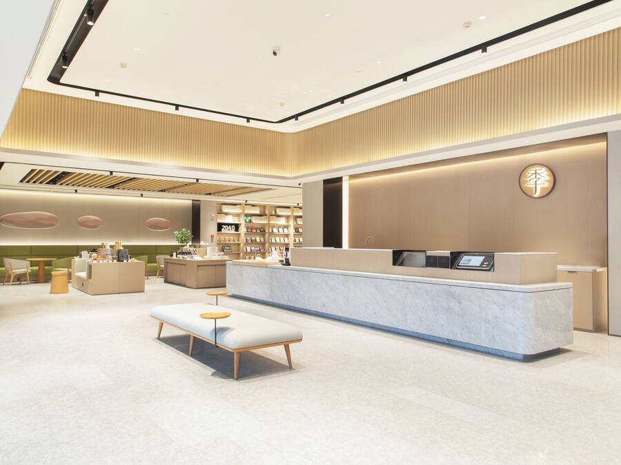 A modern hotel lobby with a reception desk, seating area, and a large bookshelf.