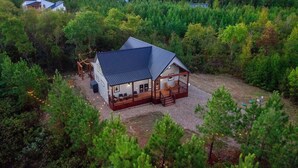Une cabane dotée d’une terrasse, entourée d’une forêt dense.