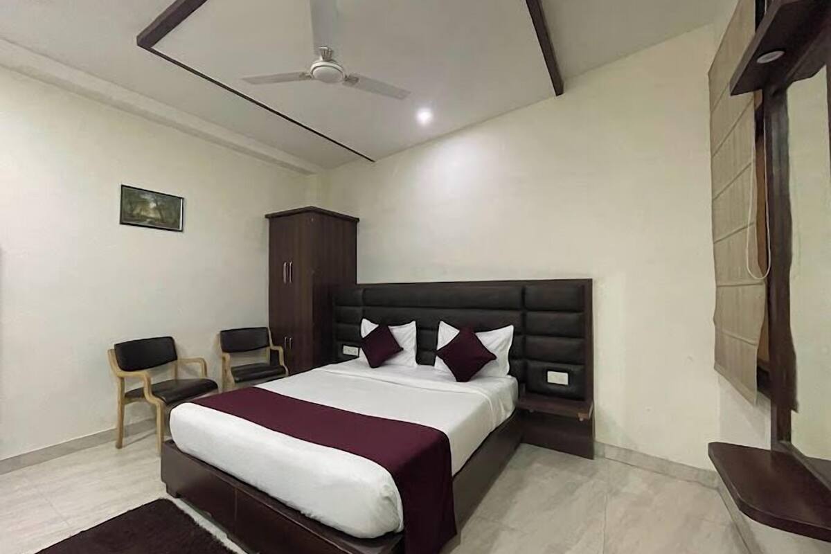 Quarto com cama, guarda-roupa, cadeira, ventoinha no teto e um quadro na parede.